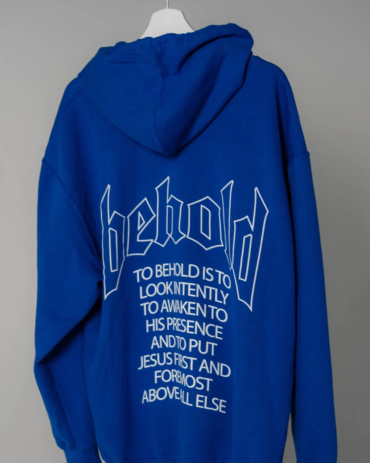 Royal blue Behold hoodie, back with the “behold” graphic