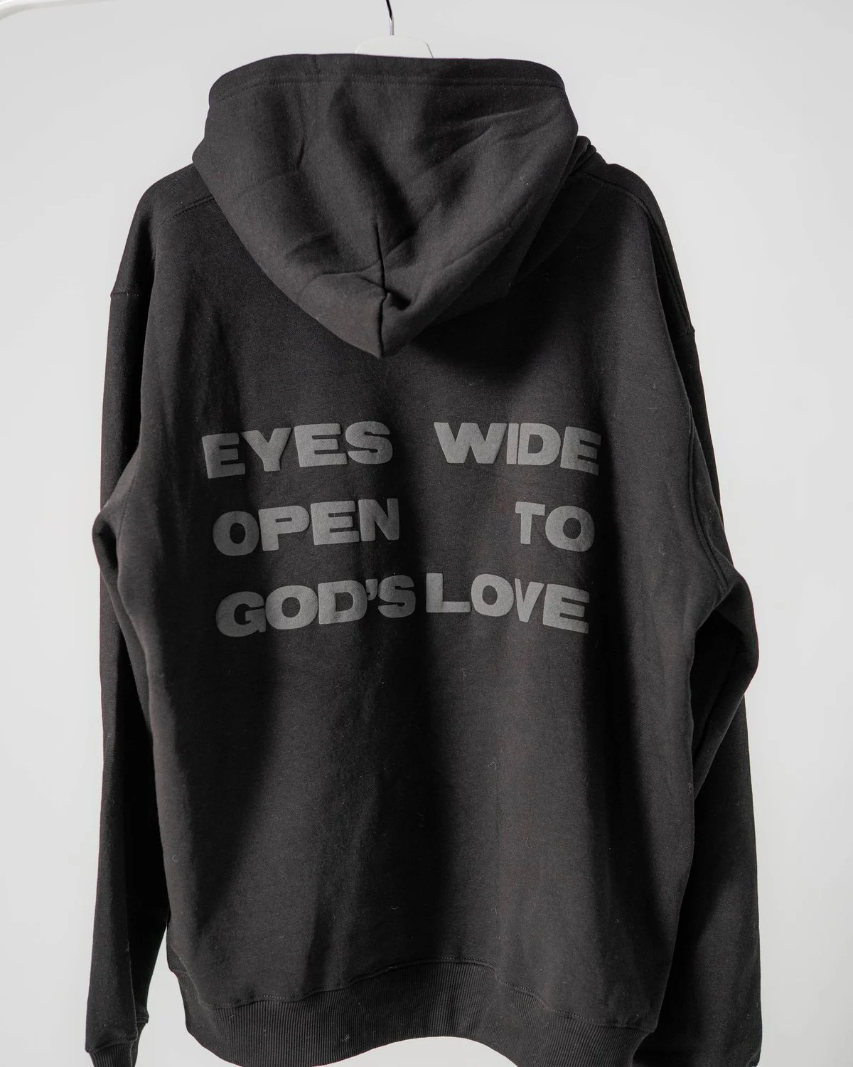 Black Eyes Open hoodie, back: “Eyes wide open to God's love” in black puff print